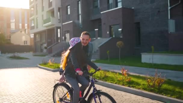 Pappa lär dottern cykla i solnedgången. Lycklig far gläds åt att hans dotter lärde sig cykla. Långsamma rörelser — Stockvideo