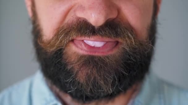Primer plano de la boca de un hombre barbudo masticando chicle. Hombre soplando una burbuja de goma de mascar — Vídeos de Stock
