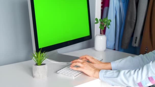 Frau tippt im Home Office auf einer Computertastatur, Monitor mit grünem Bildschirm. Chroma-Schlüssel. Kopierraum. — Stockvideo