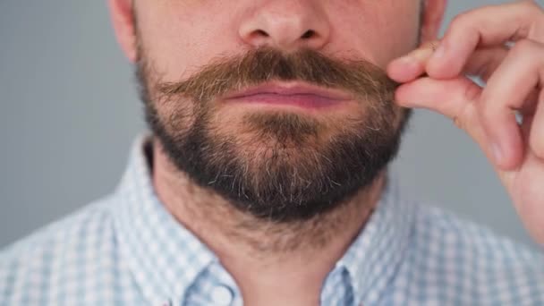 Bearded man twists his mustache and cuts it off with scissors. — Stock Video