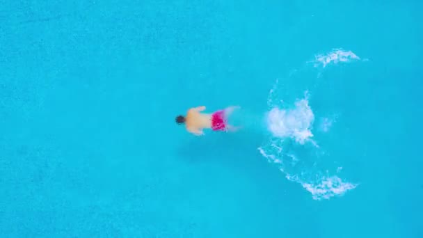 Bir adam dalışlar havuza ve altında yüzüyor gibi en baştan görüntülemek su. — Stok video