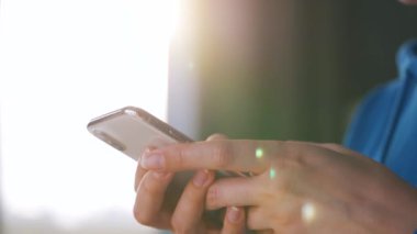 Batan güneşe karşı akıllı telefon kullanan kadın eller..