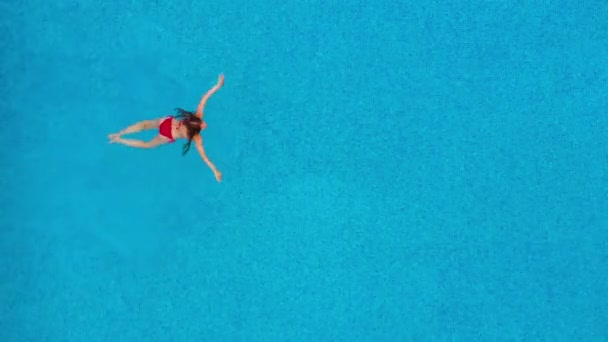Vue du haut comme une femme en maillot de bain rouge nage dans la piscine — Video
