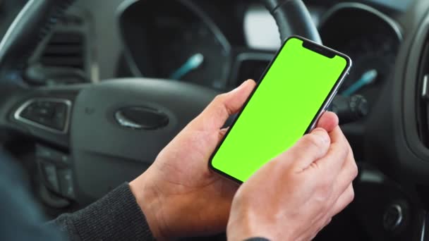 Motorista usando um smartphone dentro do carro. Smartphone Chromakey com tela verde. Navegação automática. Vício em Internet — Vídeo de Stock