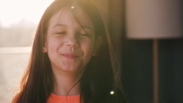 Porträtt av en brunett flicka tittar på kameran och ler mot solnedgången — Stockvideo