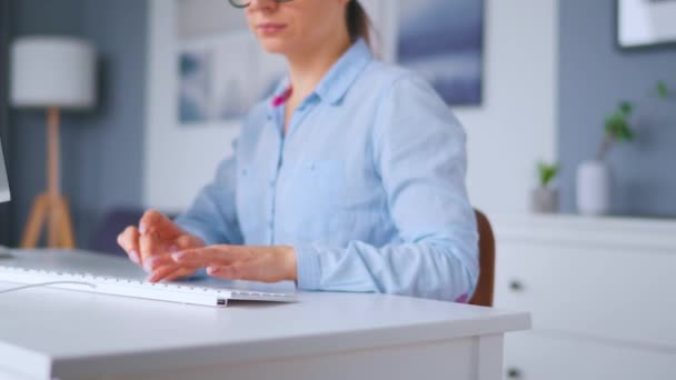 Mujer con gafas escribiendo en el teclado de un ordenador. Concepto de trabajo remoto. — Vídeos de Stock