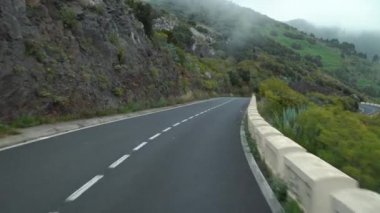Bulut seviyesinde bir dağ yolunda ilk kişi görüntüsü, yeşil bitki örtüsü ve yüksek nem ile kaplı yamaçlar. Kanarya Adaları, İspanya.