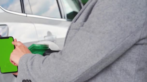 Kvinnen bruker en mobilapplikasjon i en smarttelefon for å betale for å fylle drivstoff på en bil. Smarttelefon med grønn skjerm. Kromnøkler – stockvideo