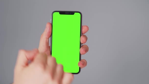 Mãos masculinas usando um smartphone com uma tela verde em um fundo cinza. Chave Chroma — Vídeo de Stock