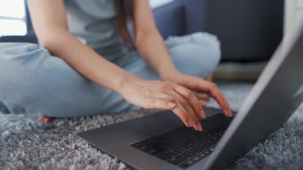 La donna e 'seduta sul pavimento e sta lavorando su un portatile. Concetto di lavoro a distanza. — Video Stock