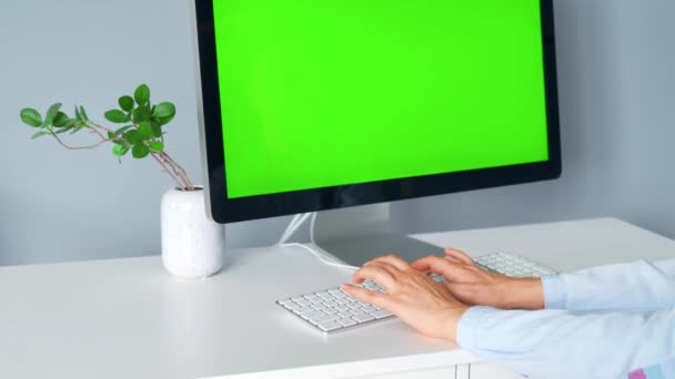 Mujer escribiendo en un teclado de ordenador, monitor con una pantalla verde. Clave de croma. Copiar espacio. — Vídeos de Stock