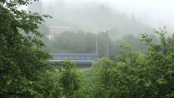 Il vecchio treno passeggeri attraversa un paesaggio montuoso coperto da una fitta nebbia — Video Stock