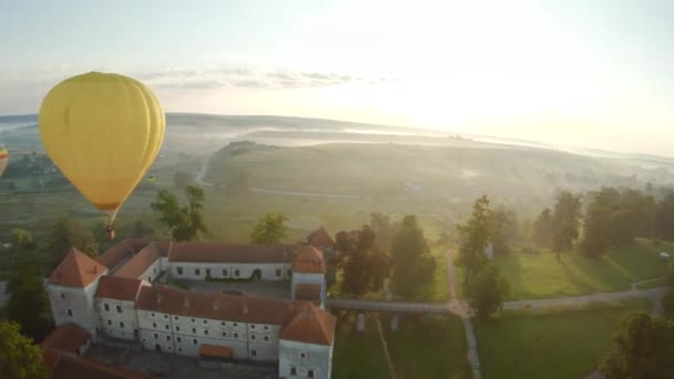 カラフルな熱気球が中世の城と朝の霧の中で湖を飛んでいます。操縦可能な飛行とパワーループ。旅行、冒険、祭り. — ストック動画