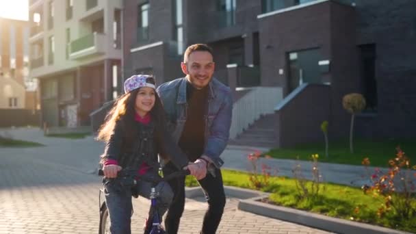 Apa megtanítja a lányát biciklizni naplementekor. Lassú mozgás. — Stock videók