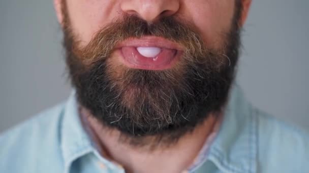 수염을 기른 사람의 입을 감싼 채 껌을 씹고 있다. 인간이 버블 껌 한 방울을 날려 보내는 모습 — 비디오