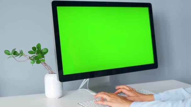 Mujer escribiendo en un teclado de ordenador, monitor con una pantalla verde. Clave de croma. Copiar espacio. — Vídeo de stock
