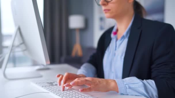 Kvinne med briller som skriver på et datamaskintastatur. Fjernarbeidsbegrep. – stockvideo