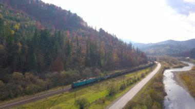 Dağlarda sonbahar: ormanla kaplı dağlar, yolda trafik ve demiryolunda tren yolculukları. Hava görünümü