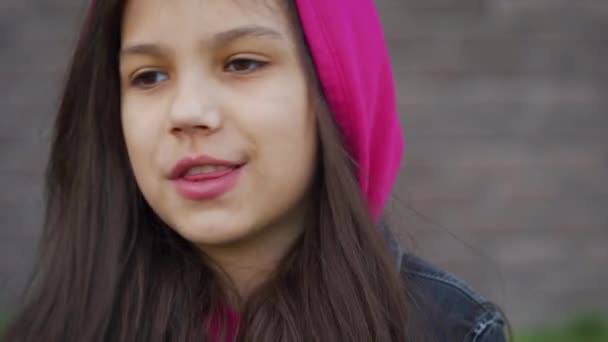 Портрет веселой брюнетки в розовом капюшоне разговаривает с кем-то за кулисами — стоковое видео