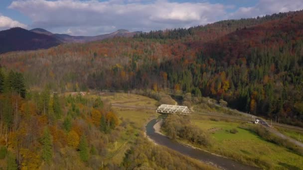 Vista da altura na paisagem de montanha de outono - floresta amarela, rio, ponte ferroviária e tráfego na estrada. Captura de vídeo a velocidades diferentes - normal e acelerada — Vídeo de Stock