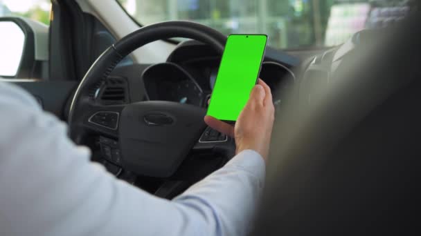 Řidič používá v autě smartphone. Chromakey smartphone se zelenou obrazovkou. Autonavigace. Internetová závislost — Stock video