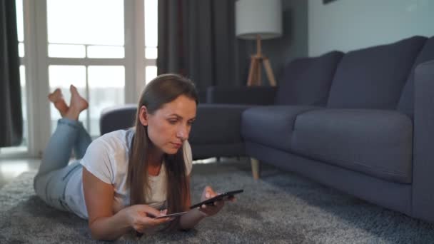 A nő fekszik a padlón, és egy online vásárlás segítségével egy hitelkártya és okostelefon. Online vásárlás, életmód technológia — Stock videók