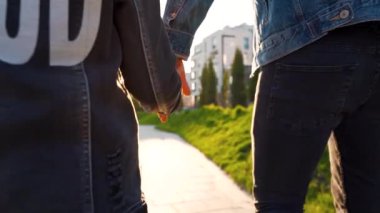 Baba ve kızı gün batımında kendi bölgelerinde dolaşırlar. Çocuk babasının elini tutuyor.