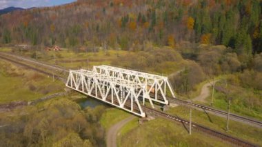 Sonbahar dağ manzarasının yüksekliğinden bak - Sarı orman, nehir, demiryolu köprüsü ve üzerinden geçen araç