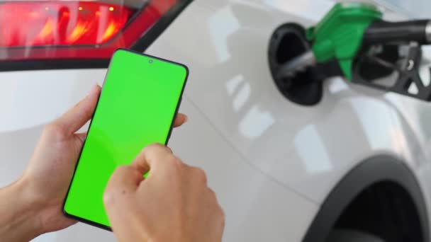 Wanita menggunakan aplikasi ponsel di smartphone untuk membayar pengisian bahan bakar mobil. Smartphone dengan layar hijau. Kunci kroma — Stok Video