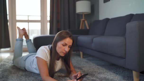 A nő fekszik a padlón, és egy online vásárlás segítségével egy hitelkártya és okostelefon. Online vásárlás, életmód technológia — Stock videók