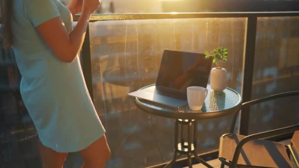 Woman works on the balcony against the backdrop of the sunset. Remote work concept — Stock Video