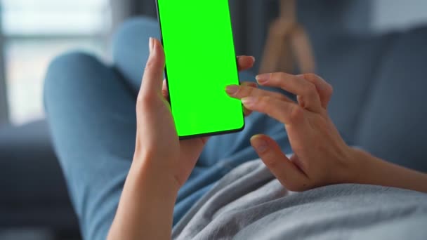 Жінка вдома лежала на дивані і використовувала смартфон з зеленим макетом у вертикальному режимі. Дівчинка переглядає Інтернет, переглядає контент, відео, блоги. ПОВ. — стокове відео
