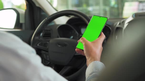 Bestuurder met behulp van een smartphone in de auto. Chromakey smartphone met groen scherm. Auto navigatie. Internetverslaving — Stockvideo