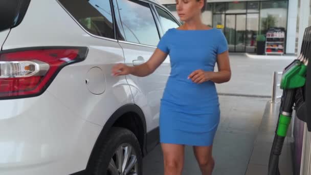 A nő betesz egy üzemanyag pisztolyt egy benzintartályba, hogy feltöltse az autót. — Stock videók