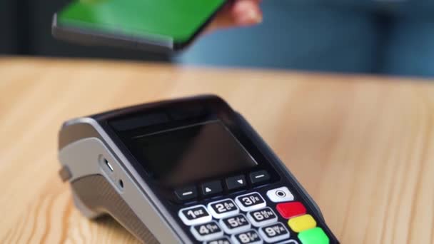 Contactless payment with smartphone with green mock-up screen. Wireless payment concept. Close-up, woman using smartphone cashless wallet NFC technology to pay order on bank terminal. — Stock Video