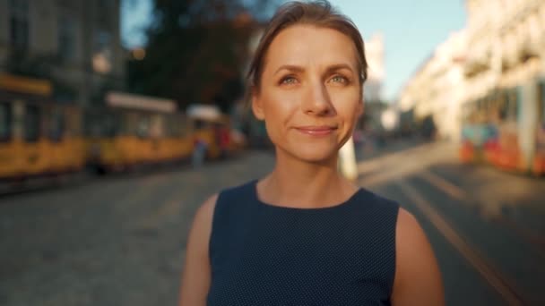 Retrato de uma mulher que fica no meio de uma praça da cidade e coloca óculos — Vídeo de Stock