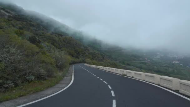 Vista en primera persona del movimiento a lo largo de un camino de montaña a nivel de nubes, pendientes cubiertas de vegetación verde y alta humedad. Islas Canarias, España. — Vídeo de stock