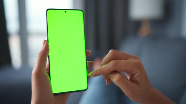 Vrouw thuis liggend op een bank en met behulp van smartphone met groene mock-up scherm in verticale modus. Meisje surfen op internet, kijken naar inhoud, video 's, blogs. POV. — Stockvideo