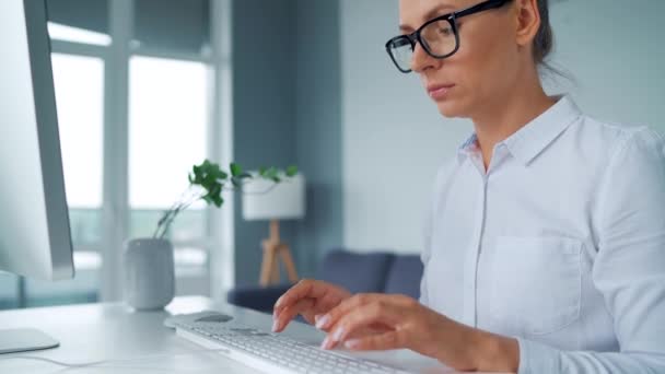 Donna in occhiali che digita su una tastiera del computer. Concetto di lavoro a distanza. — Video Stock