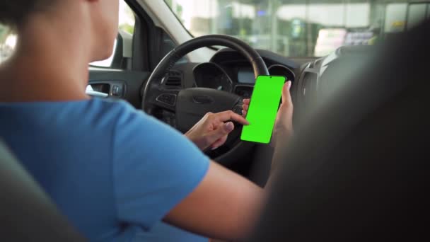 Kvinnlig förare som använder en smartphone inne i bilen. Chromakey smartphone med grön skärm. Automatisk navigering. Internetberoende — Stockvideo