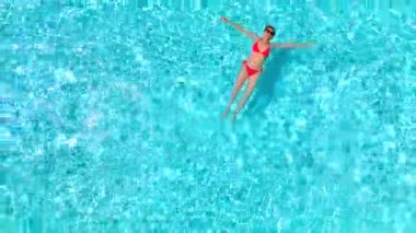 Pembe mayo giymiş bir kadının havuzda sırt üstü yatışı. Rahatlatıcı konsept, yaz yaşam tarzı. 