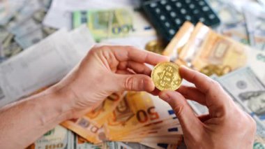 Erkek eli, farklı para birimlerinin -dolar ve avro- arka planında BTC bitcoin gösteriyor. Kripto para birimi kavramı ve engelleme teknolojisinin geniş dünyası..