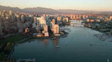 Şehir merkezindeki gökdelenlerin, dağların, False Creek 'in, tekneli marinanın havadan görüntüsü. Vancouver, British Columbia, Kanada, gün batımında.