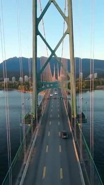 Lions Gate Köprüsü 'ndeki trafik yolunda ilham verici bir drone uçuşu. Arka planda Batı Vancouver 'ın çarpıcı doğası, British Columbia, Kanada.
