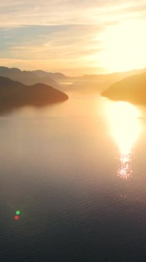 Vancouver 'ın kuzeyindeki güzel günbatımında deniz manzarası. Dağların siluetlerinin üzerine güneş batıyor. British Columbia, Kanada.