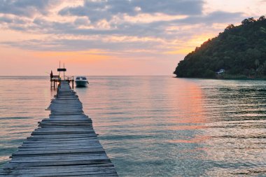 Denizin üzerinde gün batımı. Ön planda iskele