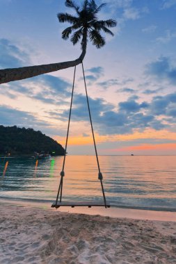 Gün batımı arka planında salıncaklı avuç içi. Tayland
