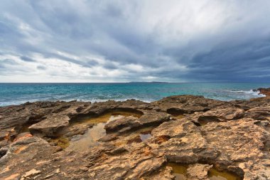 Kasvetli ve dramatik bir gökyüzünün altındaki Rocky sahili. Mallorca Adası, İspanya Akdeniz, Balear Adaları.