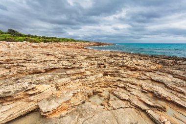 Kasvetli ve dramatik bir gökyüzünün altındaki Rocky sahili. Mallorca Adası, İspanya Akdeniz, Balear Adaları.