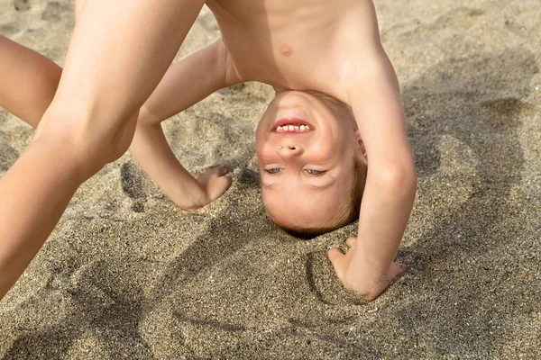 Menino de pé em sua cabeça em uma areia — Fotografia de Stock